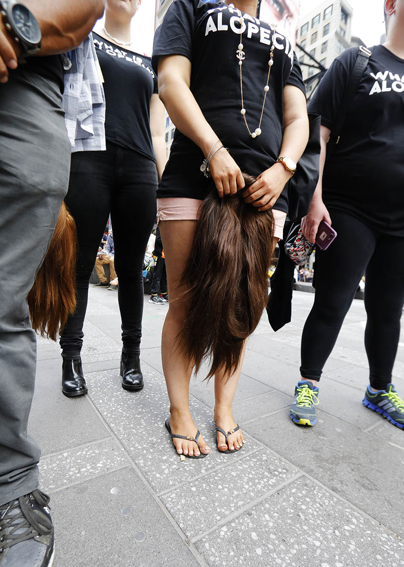 Woman Holding her wig in Times Square